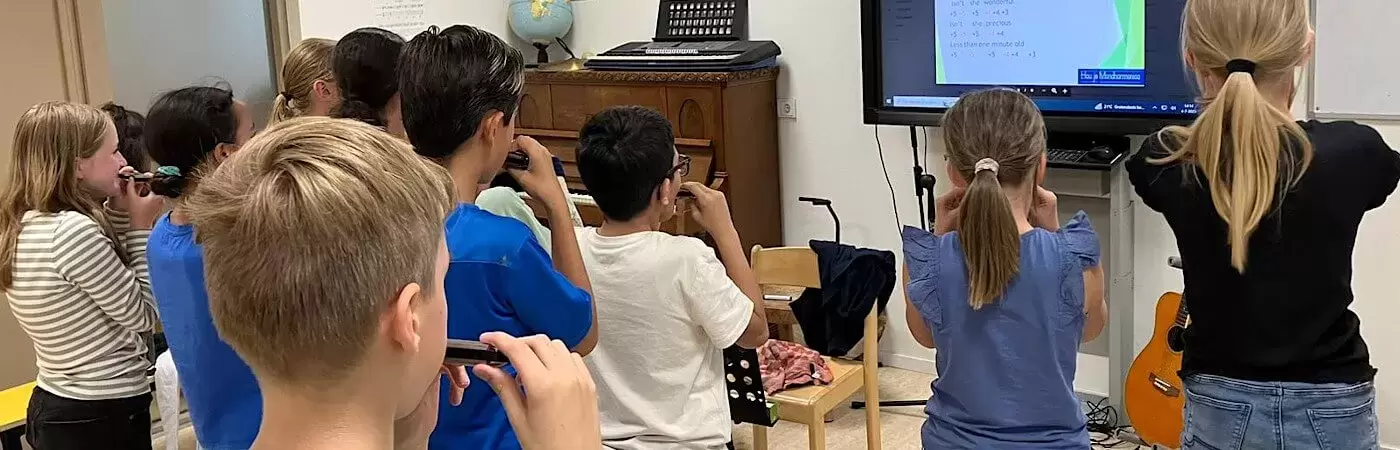 Mondharmonica leren spelen in een workshop voor groepen kinderen