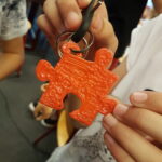 Een sleutelhanger in de vorm van een puzzelstuk gemaakt met een 3D printerpen.