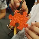 Een sleutelhanger in de vorm van een puzzelstuk gemaakt met een 3D printerpen.