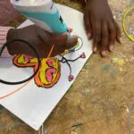 Kind die 3D printerpen gebruikt en een vlinder maakt.