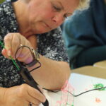 Vrouw werkt met 3D Printerpen tijdens workshop.
