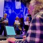 Volwassenen zingen smartlappen met begeleiding van André Bijleveld op piano tijdens een workshop.