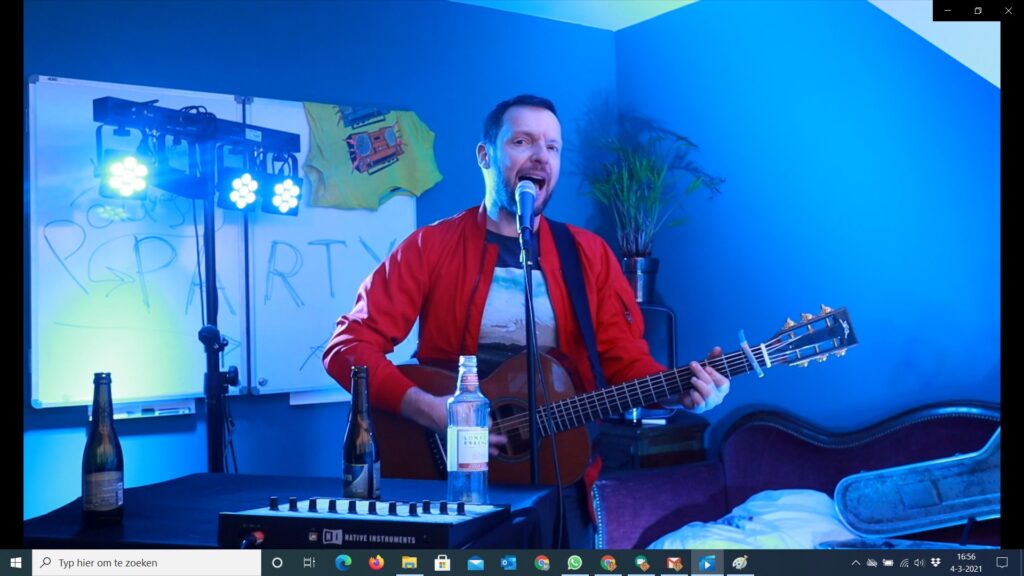 Man met gitaar in kamer met blauw licht tijdens online paasvoorstelling max music.